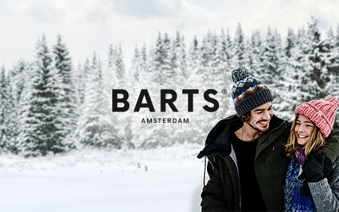 Couple in Barts hats smiling in the snow.
