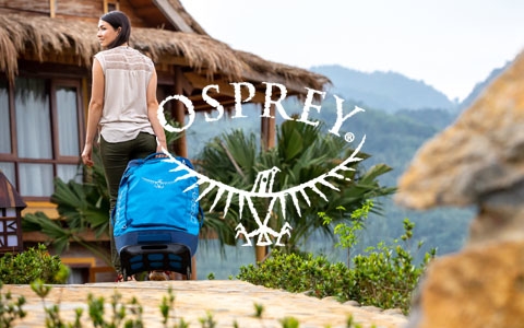 A couple with Osprey backpacks walking up a rocky hill somewhere in the mountains.
