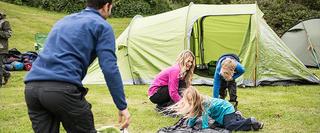 Family playes while setting up tent