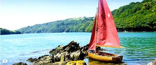 Sail Boast with Red Sail Docked on Rocks