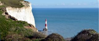 landscape view of coastal white cliffs and a small light house in the sea