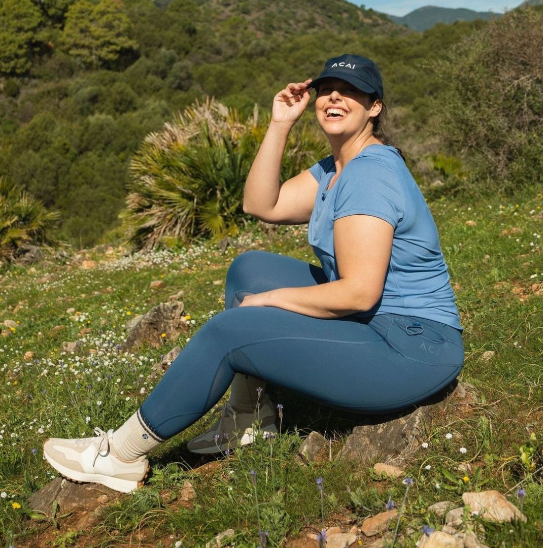 A woman sat on the grass wearing ACAI