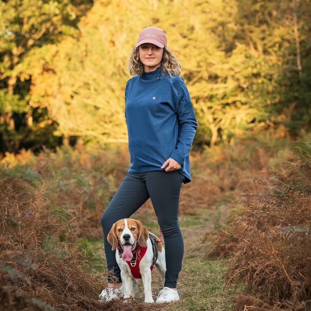 A woman stood in the countryside wearing ACAI with her dog