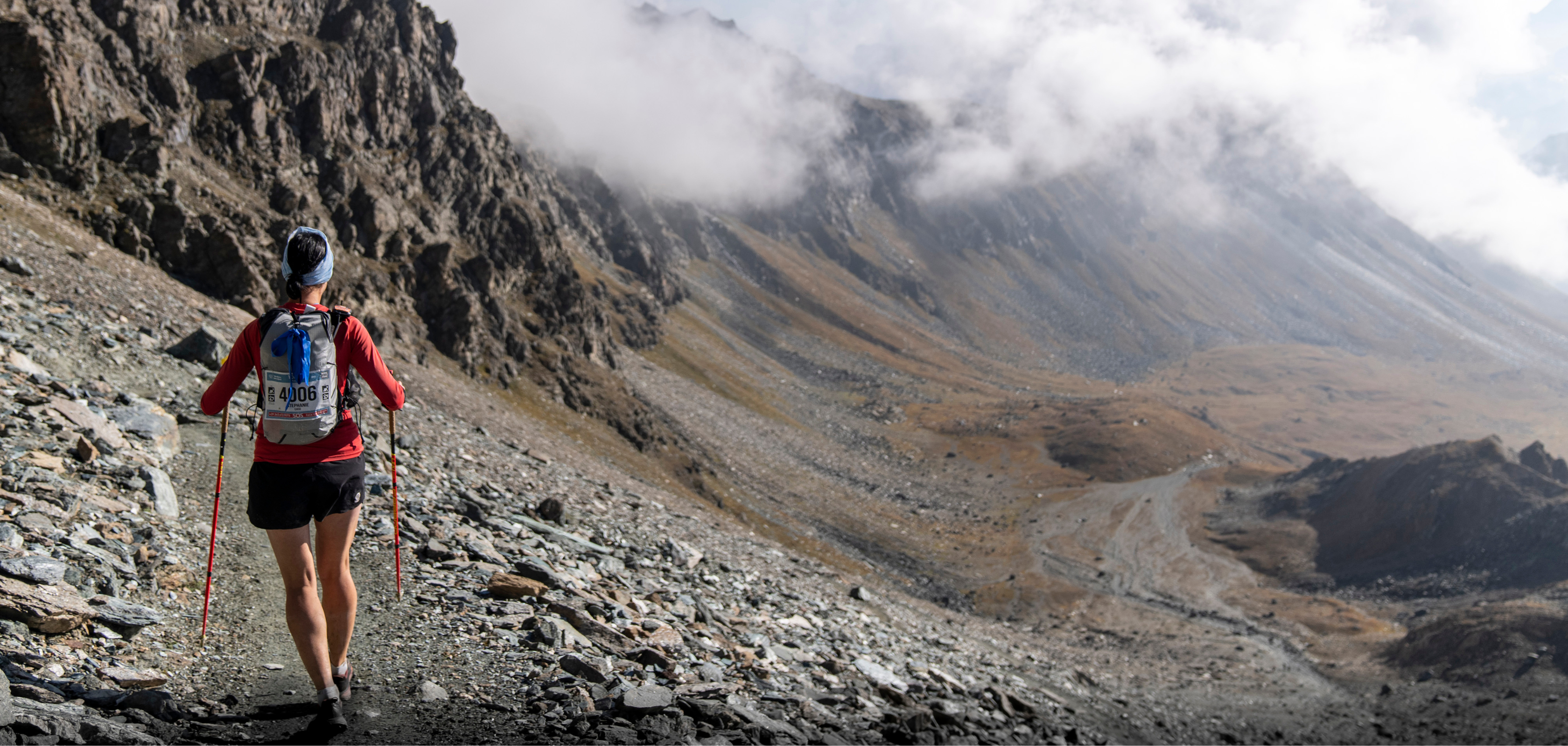 A woman in trail kit running a rugged mountain trail