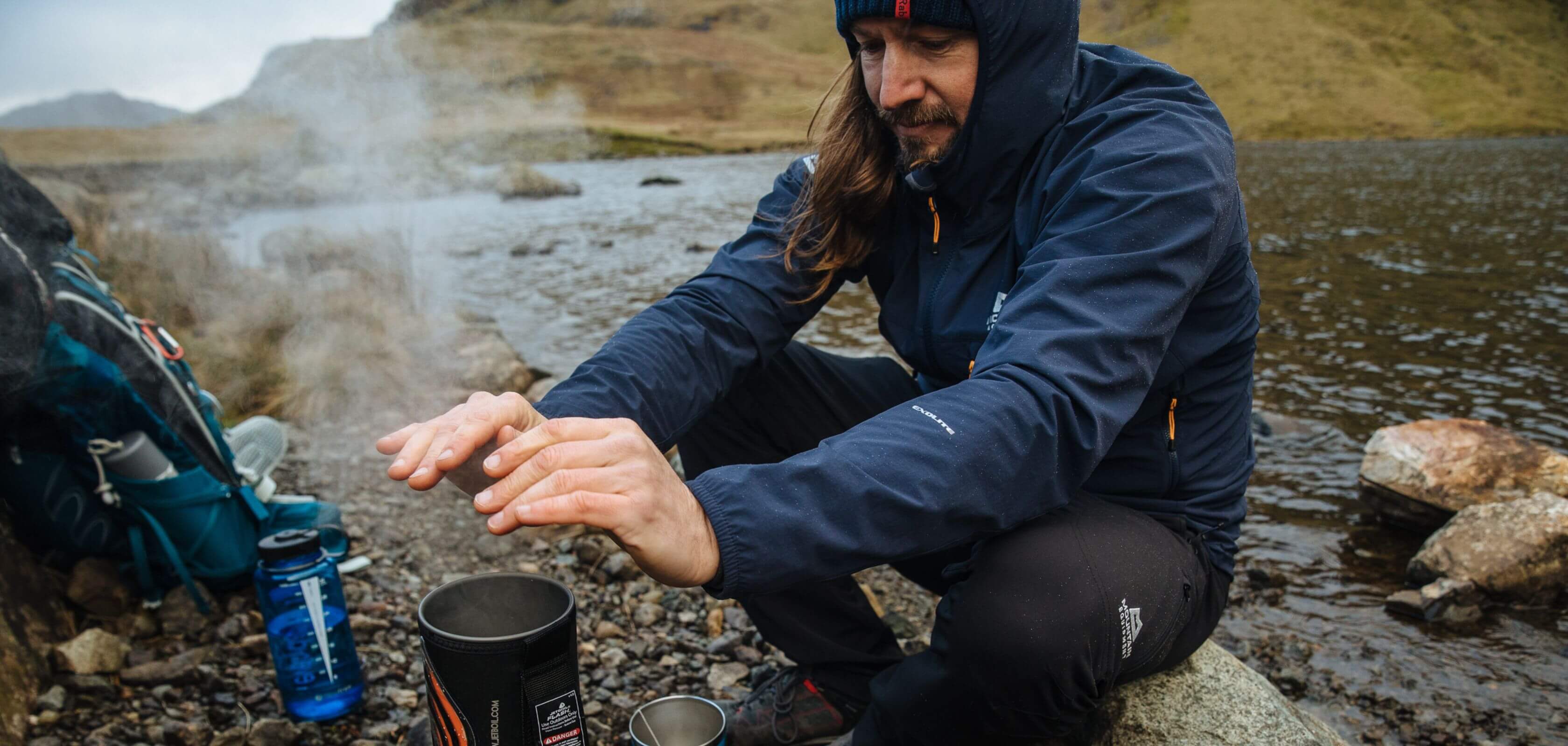 A man warming his hands over a camping stove