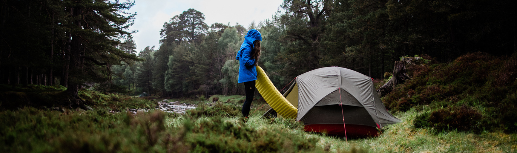 A person pitching their tent in the wilderness