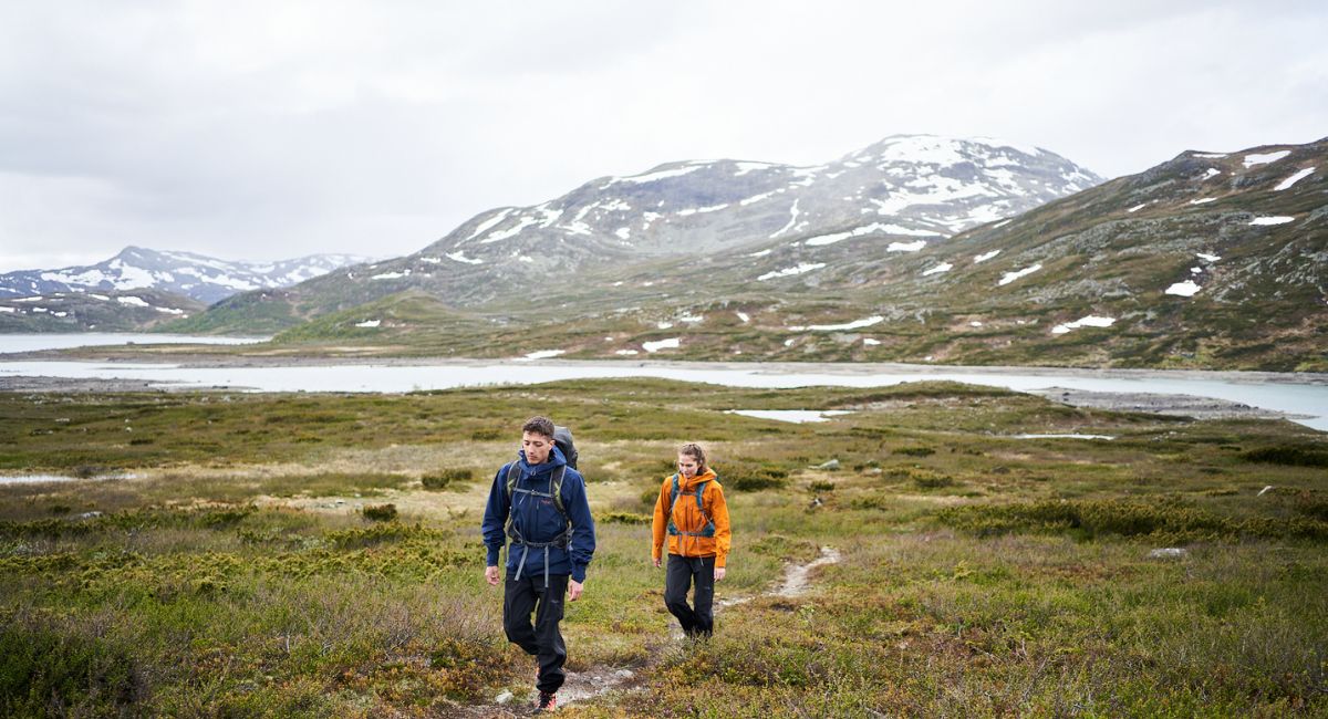 A man and woman wearing Rab clothing on a hike in the mountains
