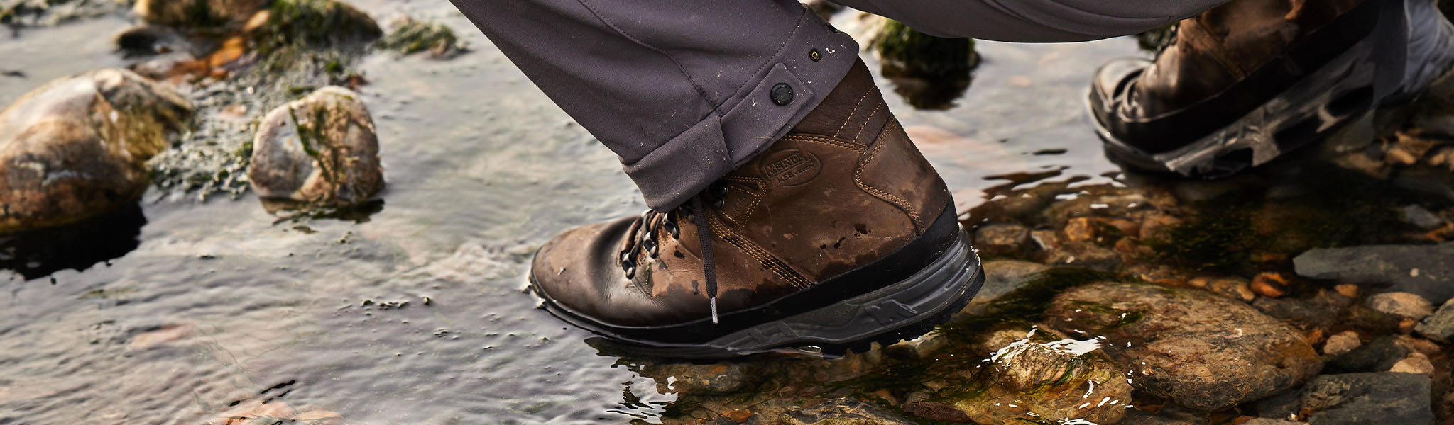 Person's brown boot is stepping into water.
