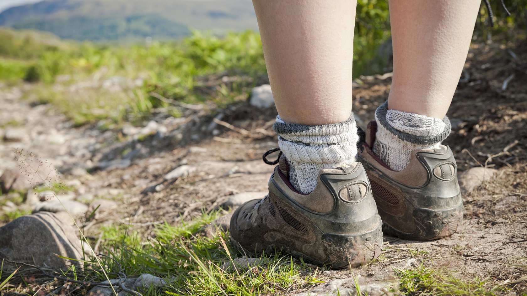 A woman's legs and muddy feet in close-up on a hiking path in Torridon, North West Scotland.
