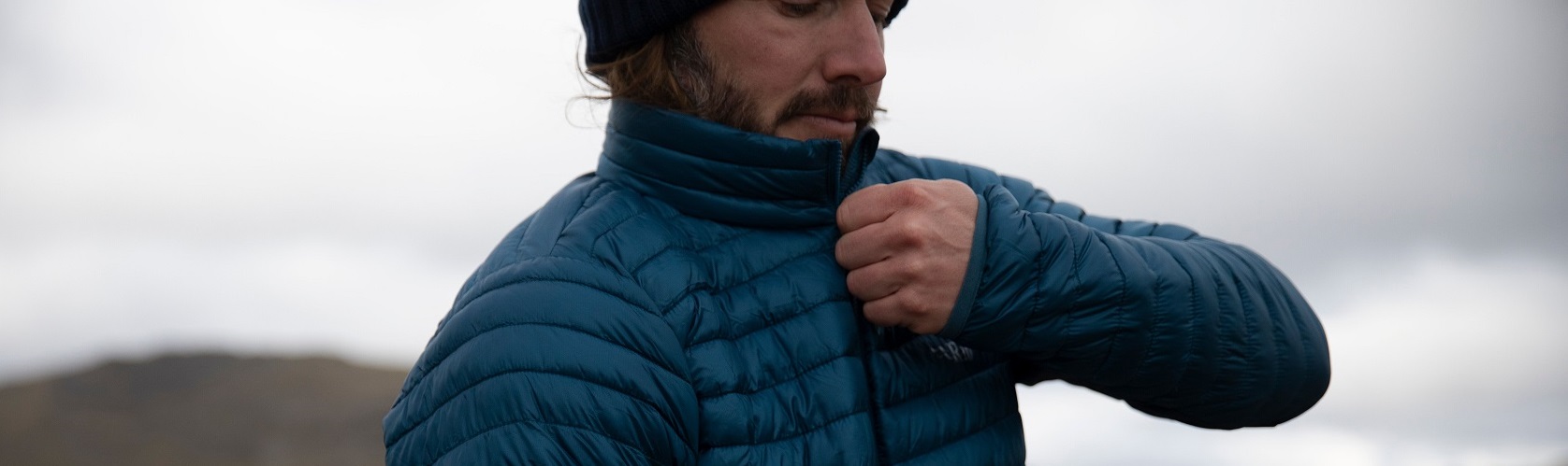 An image of a person zipping up their insulated jacket 