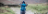 A man walking away from the camera somewhere in the countryside and putting his rucksack on.