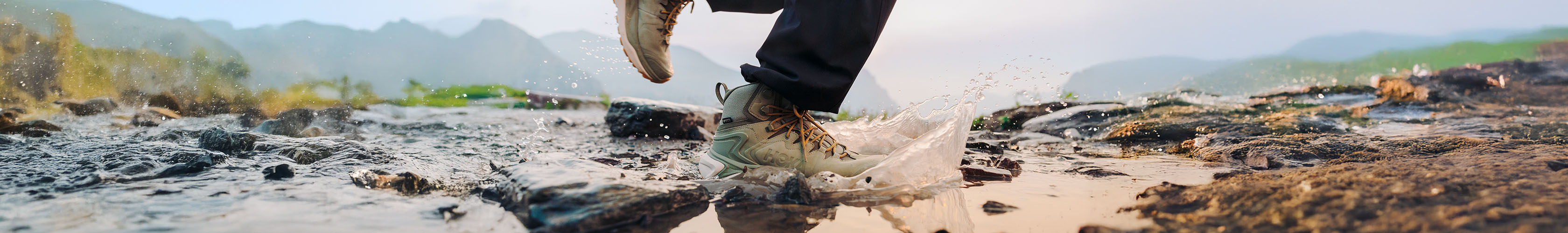HOKA shoes splashing through a rocky puddle