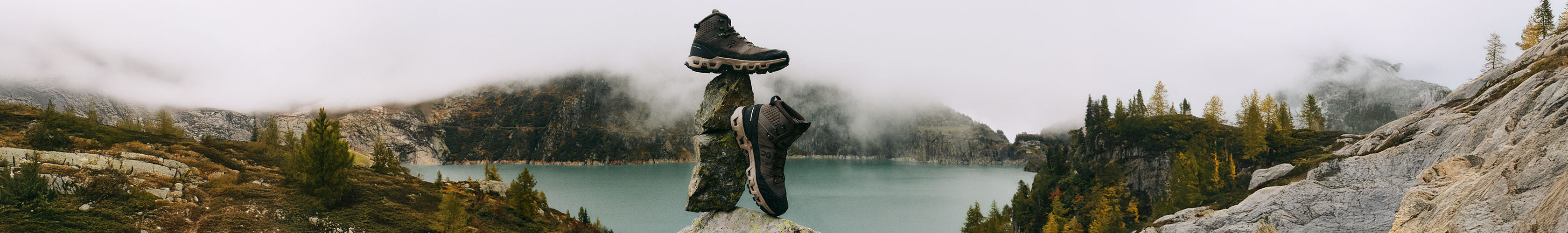 ON shoes balanced on rocks with outdoor landscape