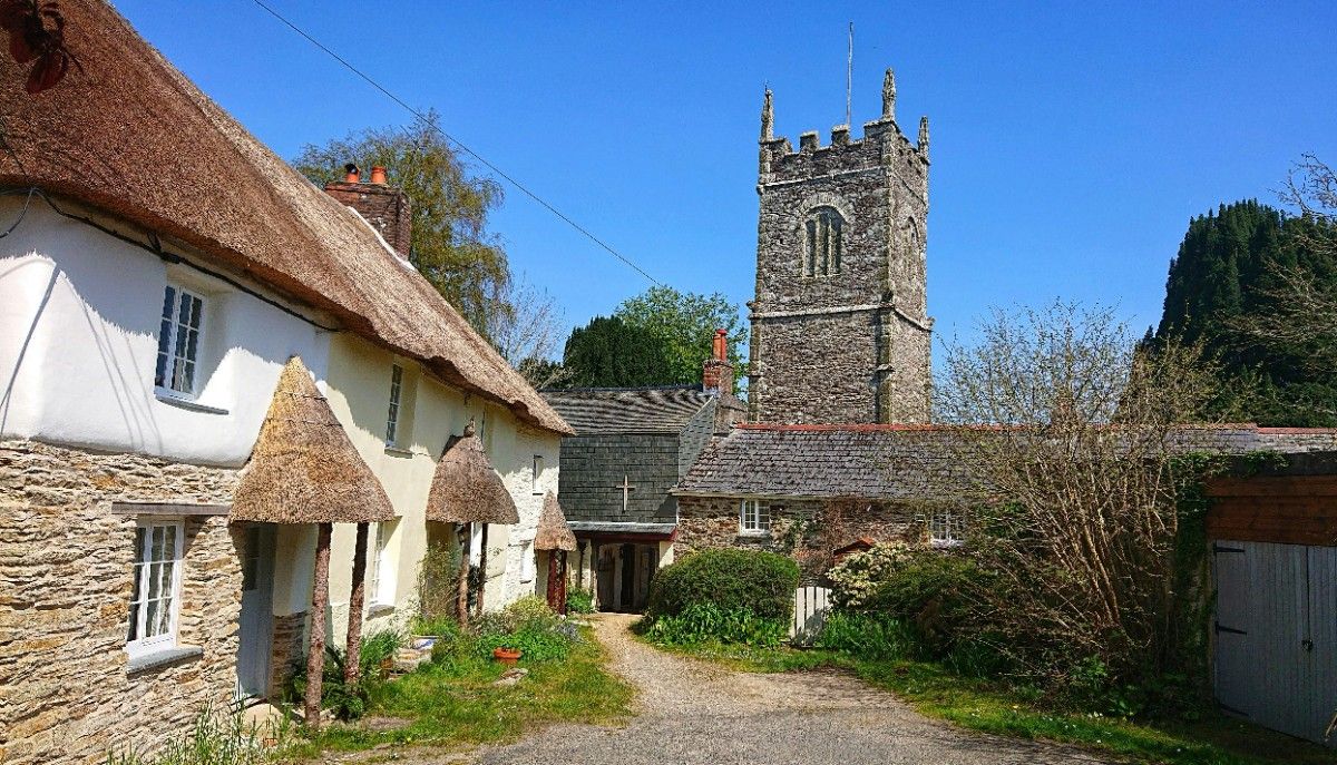 An image of a cottage with a church in the background 