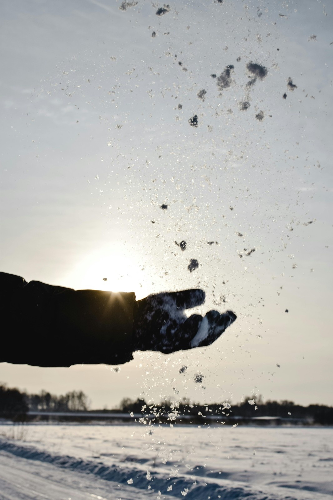A man throwing snow in the air with his gloves
