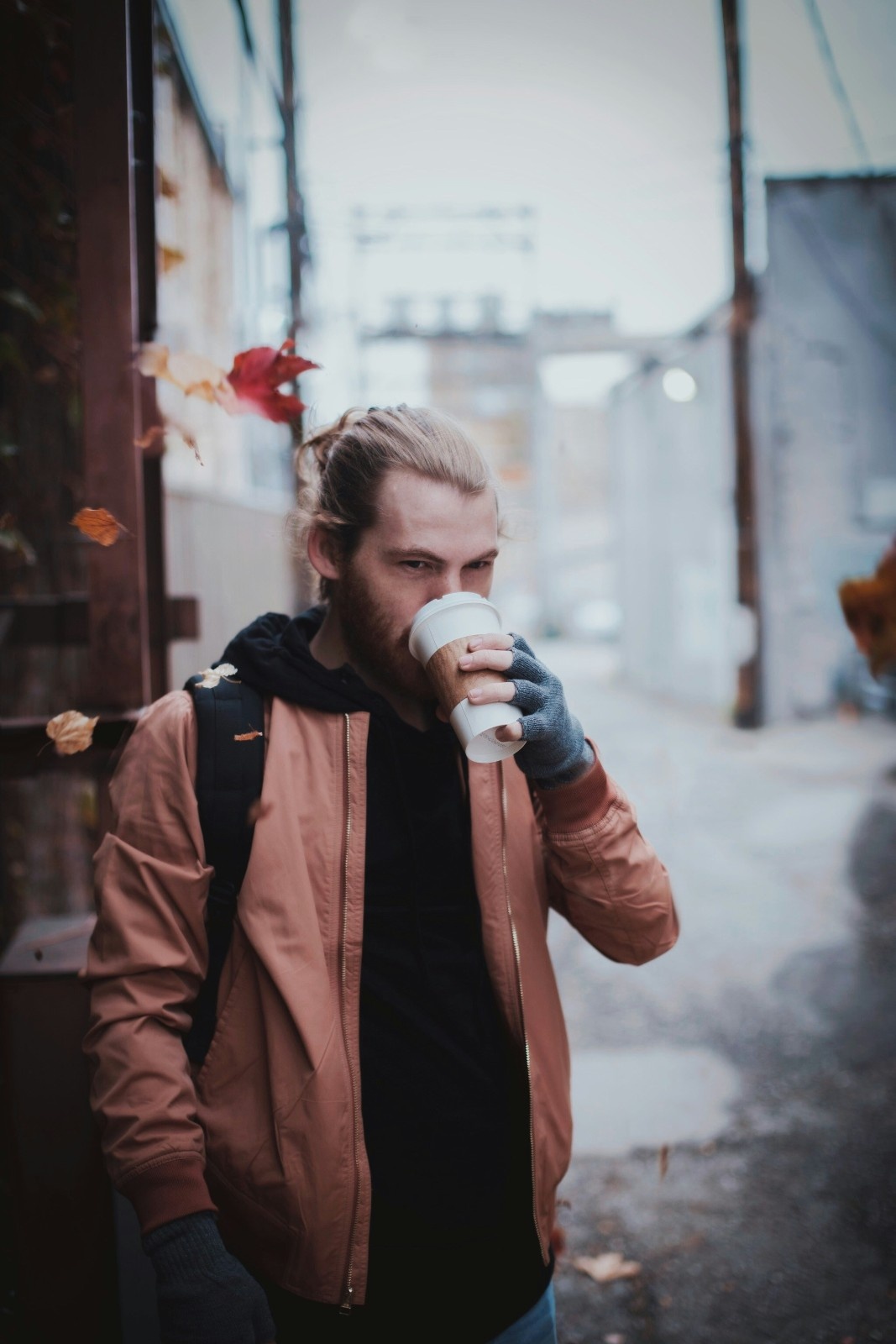 A man holding a coffee in his fingerless gloves