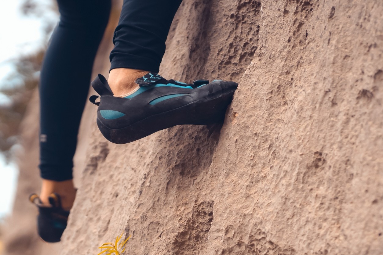 An image of a person climbing a rock in climbing shoes