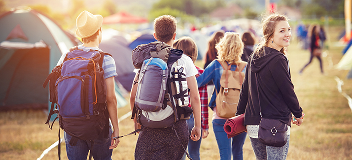 a group of friends arriving at a festival with their camping gear 